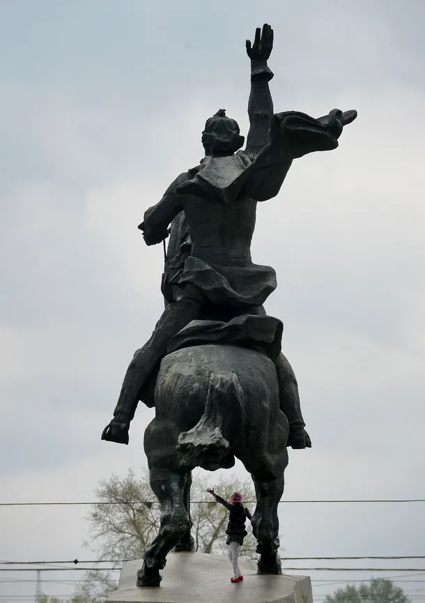 O fată se joacă sub statuia lui Aleksandr Suvorov