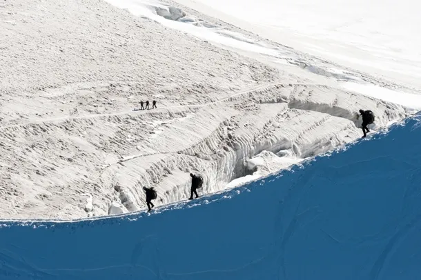 Alpinişti care parcurg iarna o tură de creastă