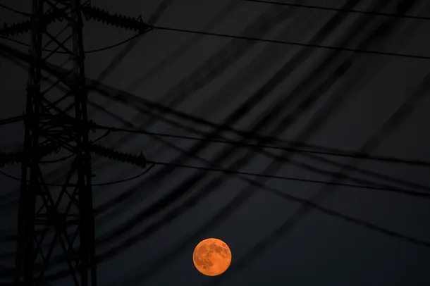Luna plina poate fi observata printre fire de inalta tensiune, in Bucuresti, duminica, 10 august 2014. 